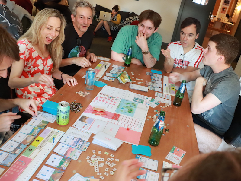 A group of six people sitting around a table playing daybreak