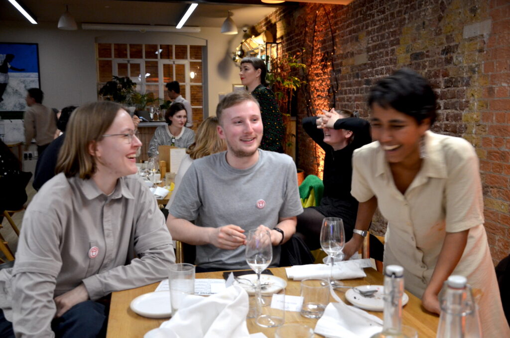 Photograph of people at dining tables chatting